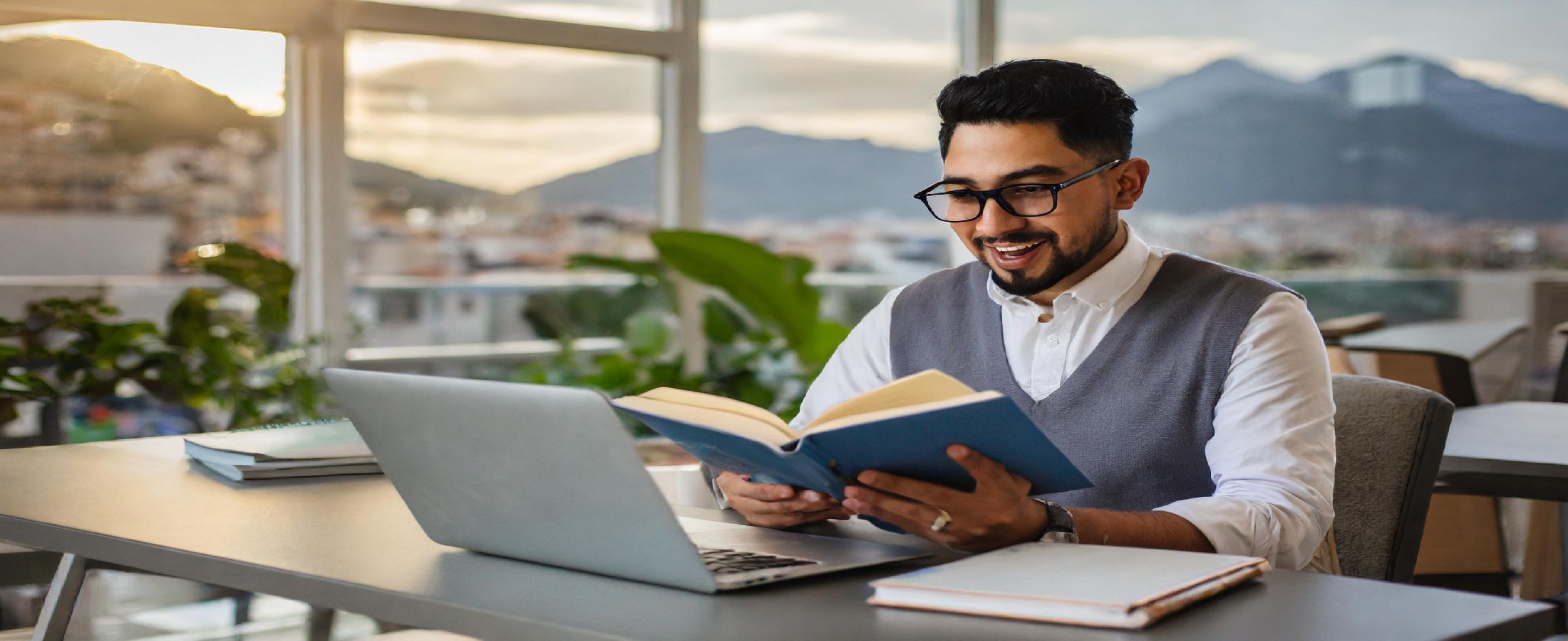 Bir kitap okuyan ve yanında bir bilgisayar bulunan bir kişi.